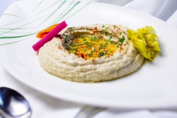 A closeup view of a plate of hummus, in a restaurant or kitchen setting.
