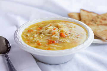 A view of a bowl of avgolemono soup, in a restaurant or kitchen setting.