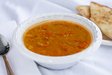 A view of a bowl of lentil soup, in a restaurant or kitchen setting.