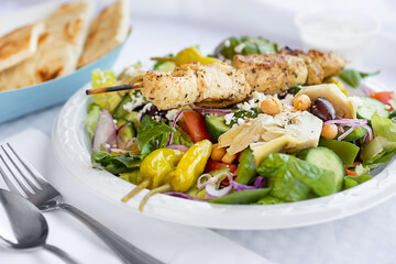 A view of a grilled chicken greek salad, in a restaurant or kitchen setting.