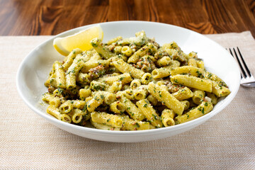 A view of a bowl of pesto pasta, in a restaurant or kitchen setting.