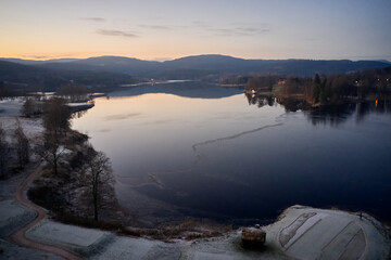 Drone or aerial photo from Oslo, Norway. Shot in late November in blue hours.  Winter is coming. Ground and trees are covered with snow frost, the lakes are freezing up.