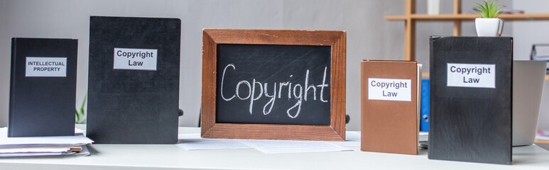 Books with intellectual property and copyright law lettering with chalkboard on table with pile of...