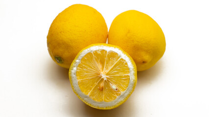 Two whole and a half cut fresh yellow lemon on a isolated white background.