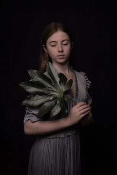 portrait of a girl in dress with a giant green leaf in dark painterly classic studio style