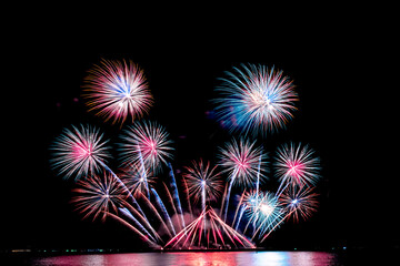The color and beautiful of fireworks set up in the sea, in the black sky at night time, for celebrating the holidays festival, to people and Happy New Year concept.