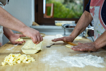Close-up of woman's hands working the dough to prepare cheese ravioli. Traditional Sardinian cuisine. Homemade.