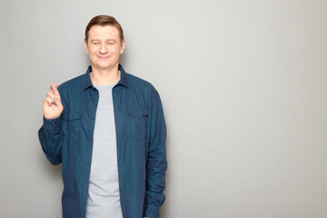 Portrait of happy man raising crossed fingers and hoping for victory