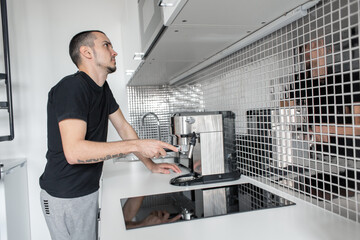 Guy prepare delicious aromatic coffee in a coffee machine. A simple way to make coffee