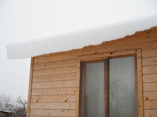 snow is hanging from the roof of the house.