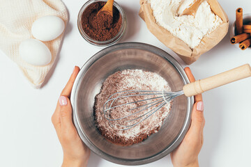 Female hands holding bowl with whisk and powder