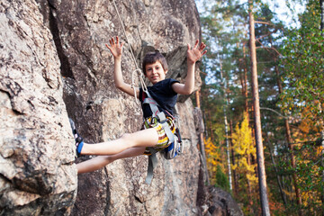 cute teen kid climbing on rock with insurance, lifestyle sport people concept