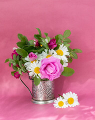 Rosehip rose and chamomile bouquet . Summer bouquet of garden flowers. Still life on the pink background