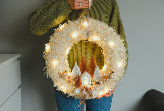 Handmade Christmas Wreath with Lights in Woman Hands for Winter holidays tradition, Lght garland, Natural and Ecofriendly Materials