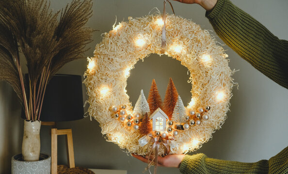Handmade Christmas Wreath with Lights in Woman Hands for Winter holidays tradition, Lght garland, Natural and Ecofriendly Materials