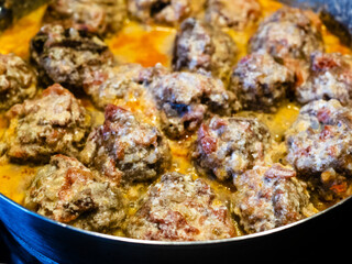 meatballs are stewed in tomato and cream sauce in saucepan close up at home kitchen