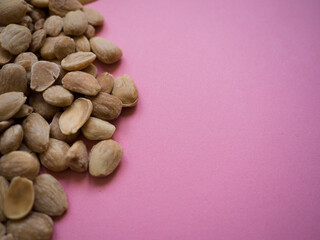 Fototapeta na wymiar Almonds on a pink background viewed from above with copy space. Health and diet concept