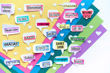 Thank You in many languages. Paper art, creative flat lay, top view on paper tags. International Thank you day. Creative background on colored layered paper.