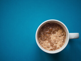 Top view a white mug with blue background. Copy space. Breakfast concept