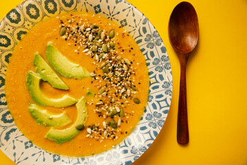 Pumpkin cream soup on a yellow background and wooden spoon
 
