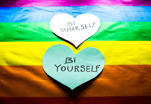 Lgbt community colorful flag. Bi yourself signs on hearts on rainbow background. Lesbian, gay and bisexual problems. Legalization of marriage for couples with homosexual orientation.