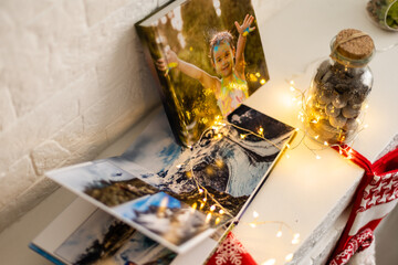 gifts, photo book and Christmas socks on the fireplace in a garland lights