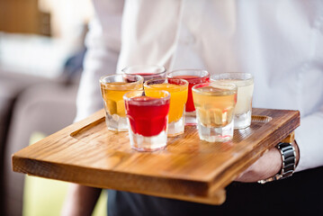 waiter with shots on wooden tray