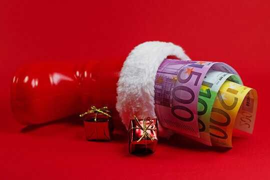 Geldscheine, Weihnachtsgeld im Nikolausstiefel vor rotem Hintergrund