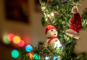 Lovely home made crochet christmas tree decoration,  snowman, with lights in the background, during Christmas holiday