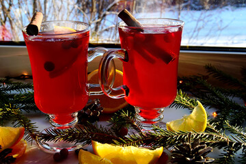 Mulled wine with spices and Christmas tree branches on a light windowsill, outside is winter....