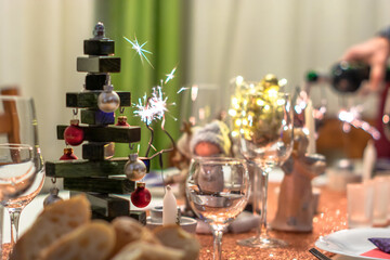 Christmas dinner table with sparkles, home made wooden christmas tree decoration, wine and food
