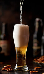 Beer in a glass glass, the foam flows down the glass. Beer publ. Beer snack - salty pretzels