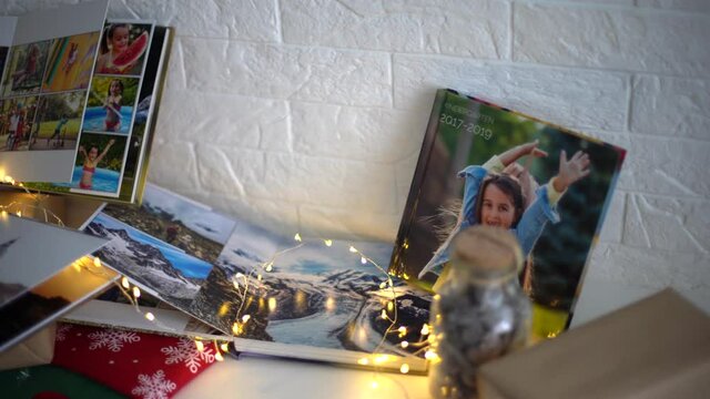 gifts, photo book and Christmas socks on the fireplace in a garland lights