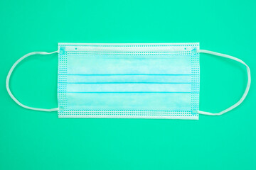 Antibacterial medical mask of blue color on a green background. Coronavirus Protection concept.