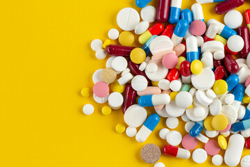 Many different pills on a yellow background. Medical concept.  Concept of threat of various diseases. Top view.