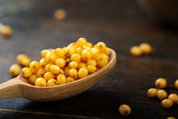 Sea buckthorn. Fresh ripe berry in wooden a spoon  on wood background.