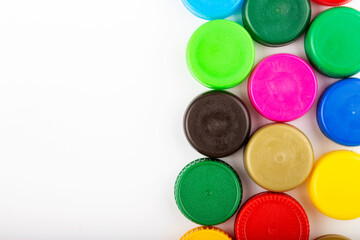 Many multi-colored plastic bottle caps on a white background.
