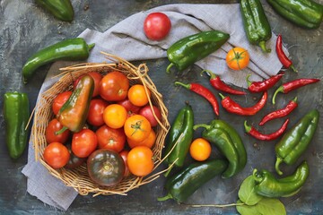 Ripe tomatoes and peppers, basket with organic fresh vegetables on the table for making healthy homemade food, top view
