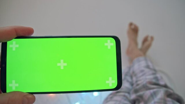 Close-up of hand holding phone with blank screen. Man at home in his free time looks at the phone doing nothing. Image of a slacker