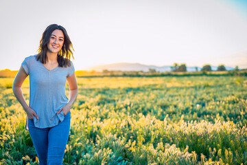 Portrait of a smiling Happy woman walking among the wild flowers in a large field on a summer evening.