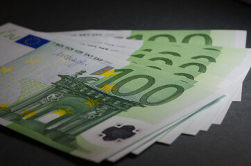 A pack of one hundred euros on a dark background, close-up in a low key. Paper money of the European Union.
