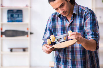 Young man repairing skateboard at workshop