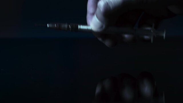 The drug addict takes the syringe from the table. Macro