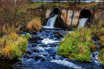 Water flows from pipes into the river. Discharge of water from the sewer. Treatment plant. Dam.