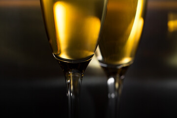 Two glasses of champagne close-up and glare. Dark background.