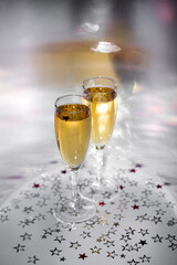 Two glasses with champagne on a shiny background and stars. New Year's sparkle.
