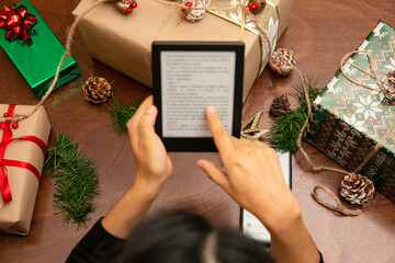 Woman reading a novel on a tablet, surrounded by Christmas gifts

Woman reading a novel on a...