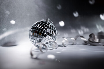 New Year's silver shiny ball and ribbon on a dark background with highlights. Christmas holidays.