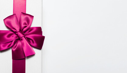Close-up of white gift box with pink bow isolated on white background with copy space for text.