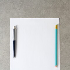 Template of white paper with a ballpoint pen and simple pencil on light grey concrete background. Concept of new idea, business plan and strategy. Stock photo with empty space for text
